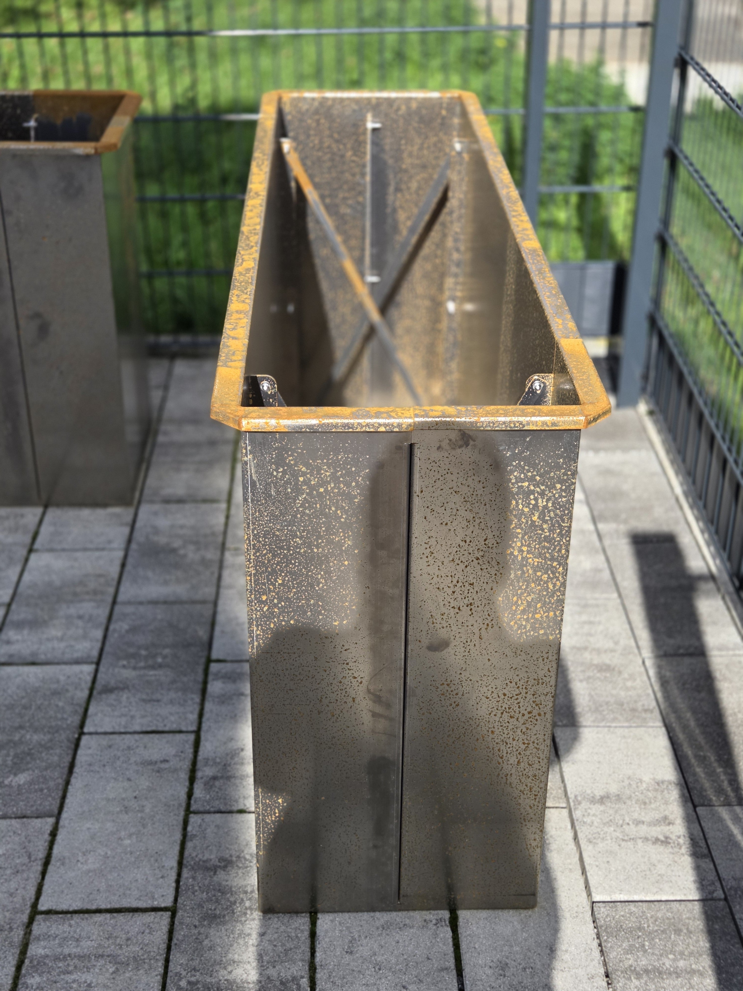 Schmales Hochbeet aus Metall auf gepflasterter Terrasse