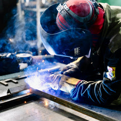 Person schweißt Metallrahmen in einer Werkstatt