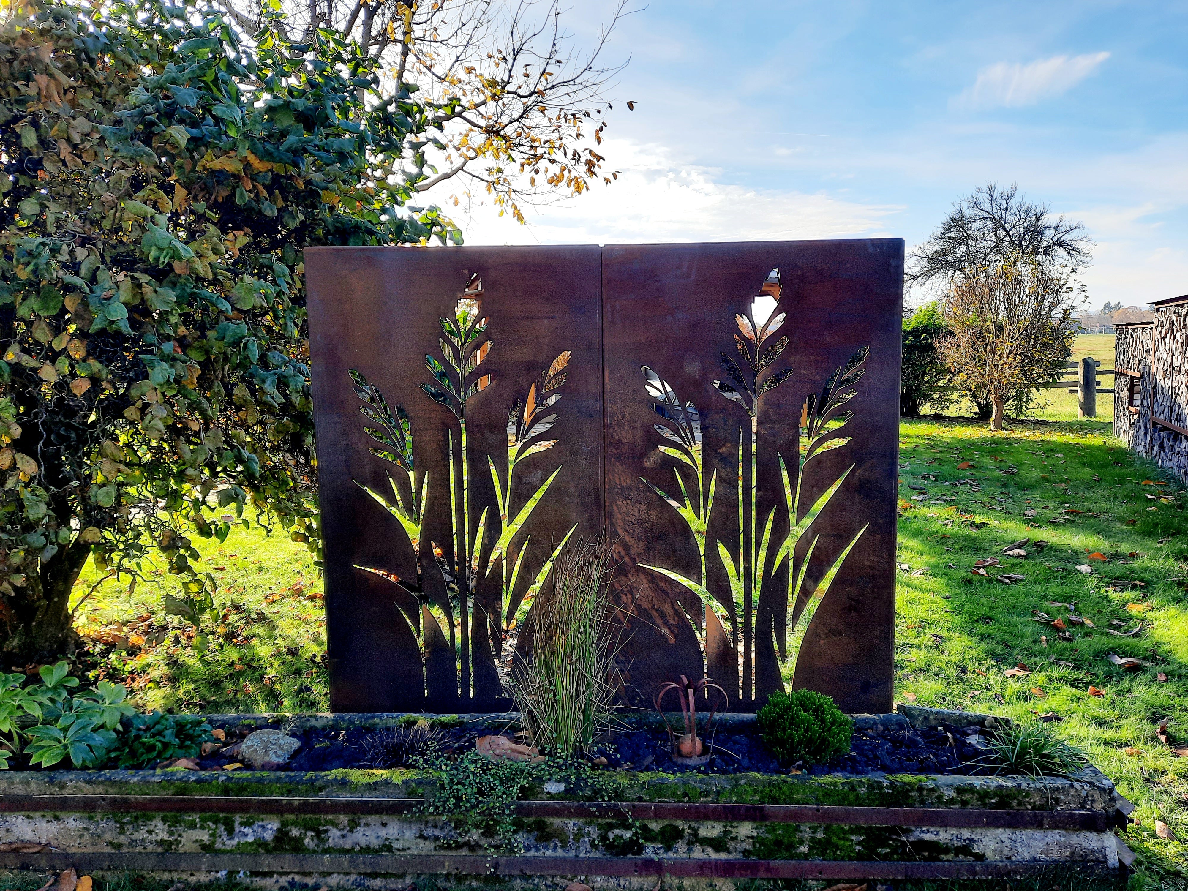 Sichtschutz aus Cortenstahl mit ausgeschnittenem Pflanzenmotiv im Garten