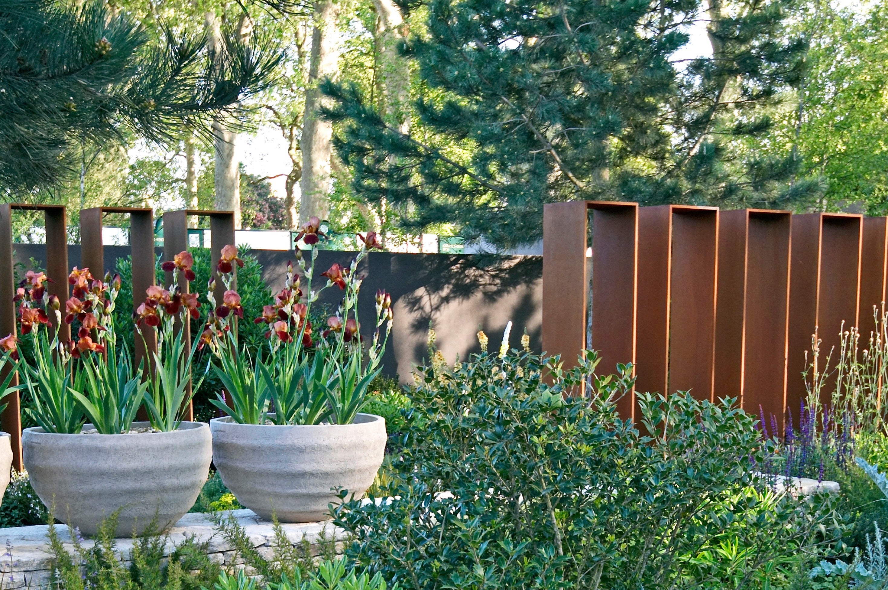 Garten mit Pflanzgefaessen, Stauden und Cortenstahl Sichtschutzelementen