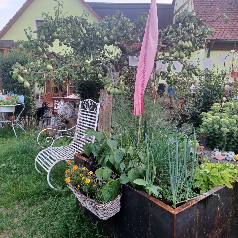 Bepflanztes Hochbeet aus Cortenstahl in einem Garten mit Sitzplatz