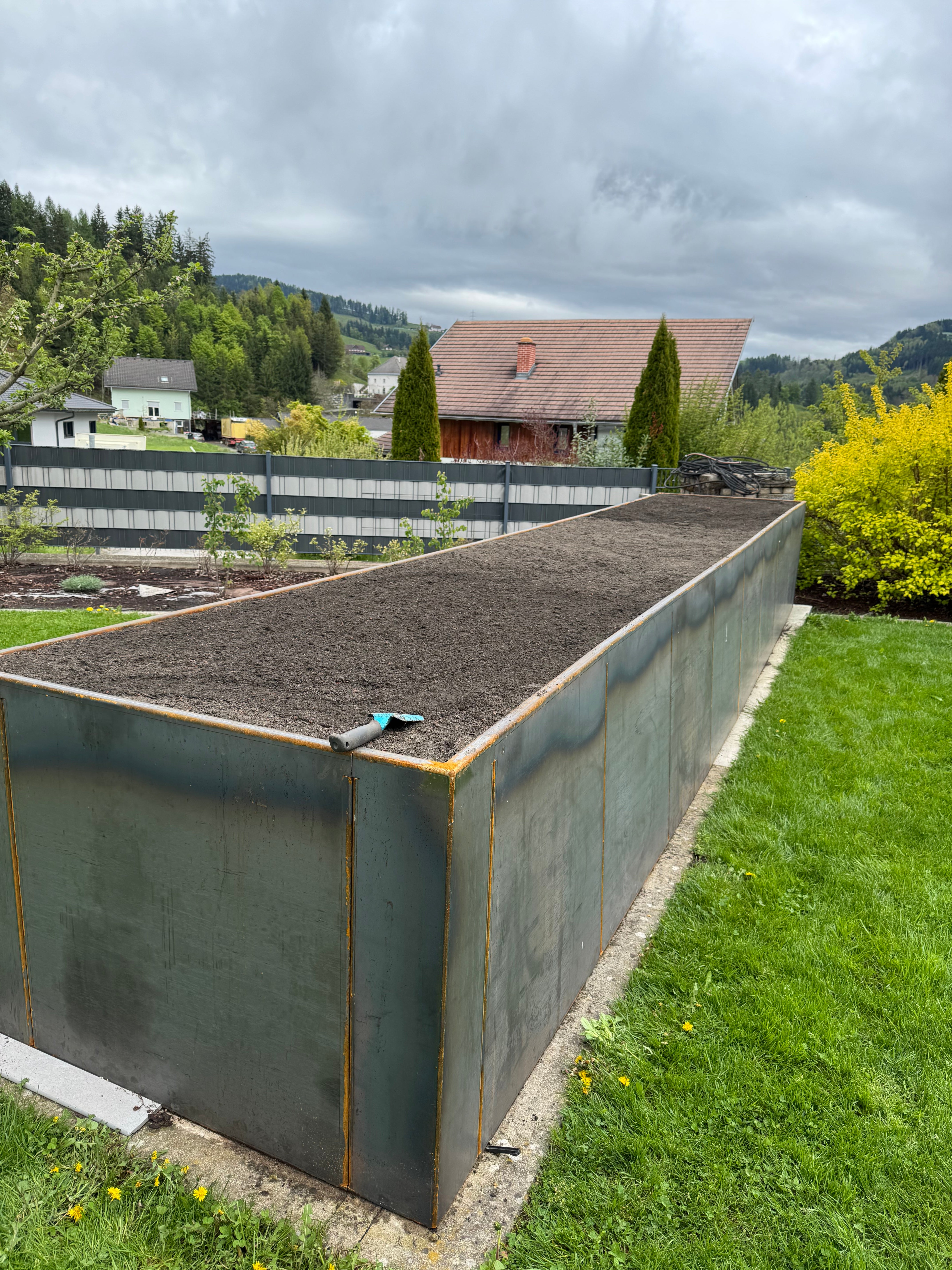 Großes Hochbeet aus Metall mit Erde im Garten