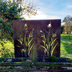 Sichtschutz aus Cortenstahl mit ausgeschnittenem Pflanzenmotiv im Garten